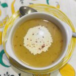 split pea souping a white bowl on a yellow striped plate.