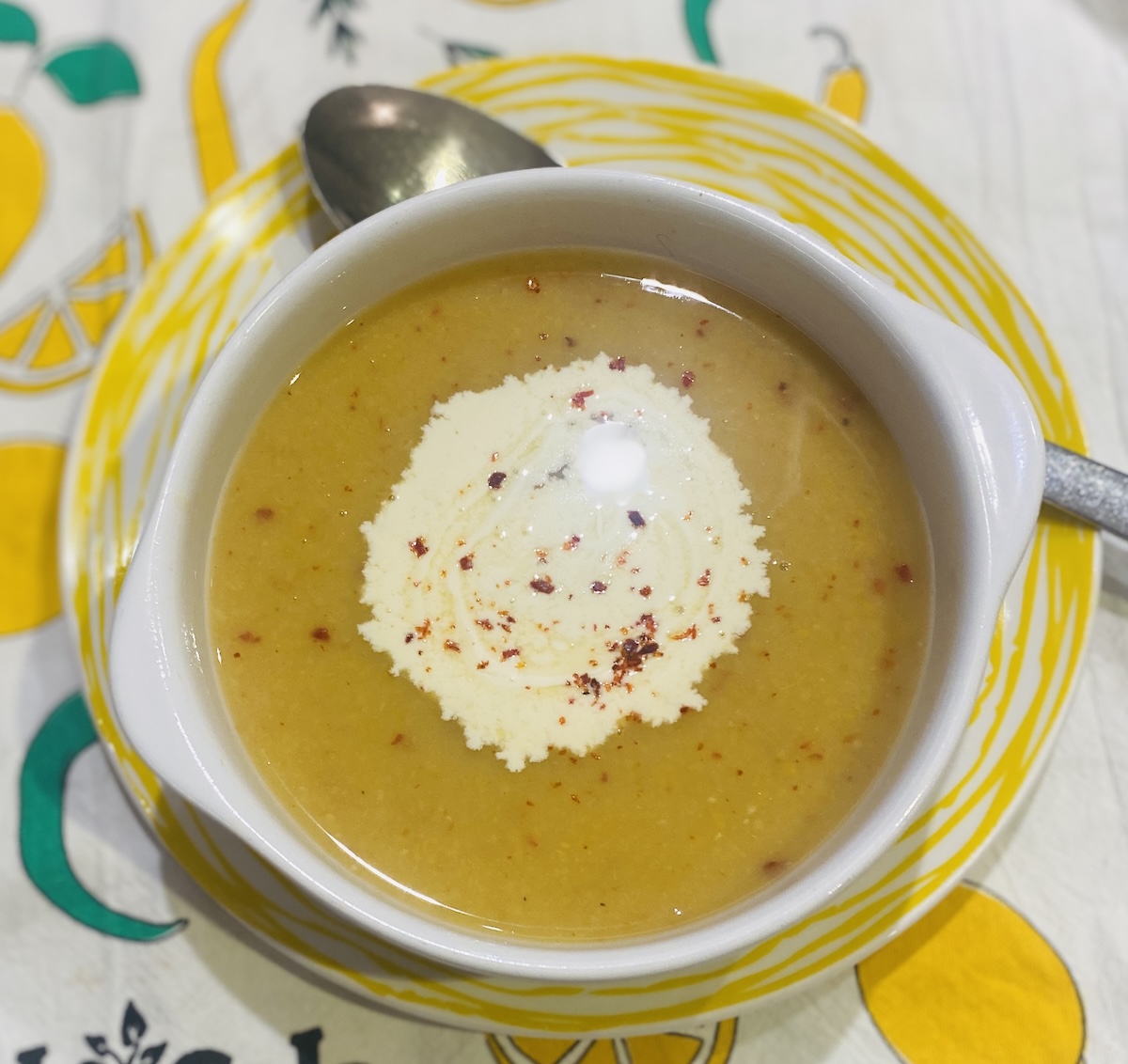 split pea souping a white bowl on a yellow striped plate.