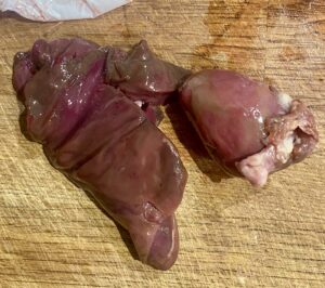 raw turkey liver and heart on a wooden chopping board.