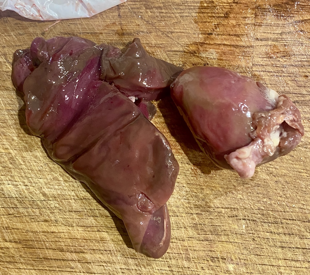 raw turkey liver and heart on a wooden chopping board. 