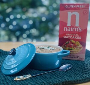 turkey liver pate in a small (250 ml) pale blue le creuset dish, on a green waffle tea-towel, with a box of oat cakes in at the background and a long handled tea spoon on the foreground
