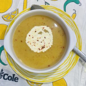 vegan split pea soup, in a white bowl, on a yellow striped plate.