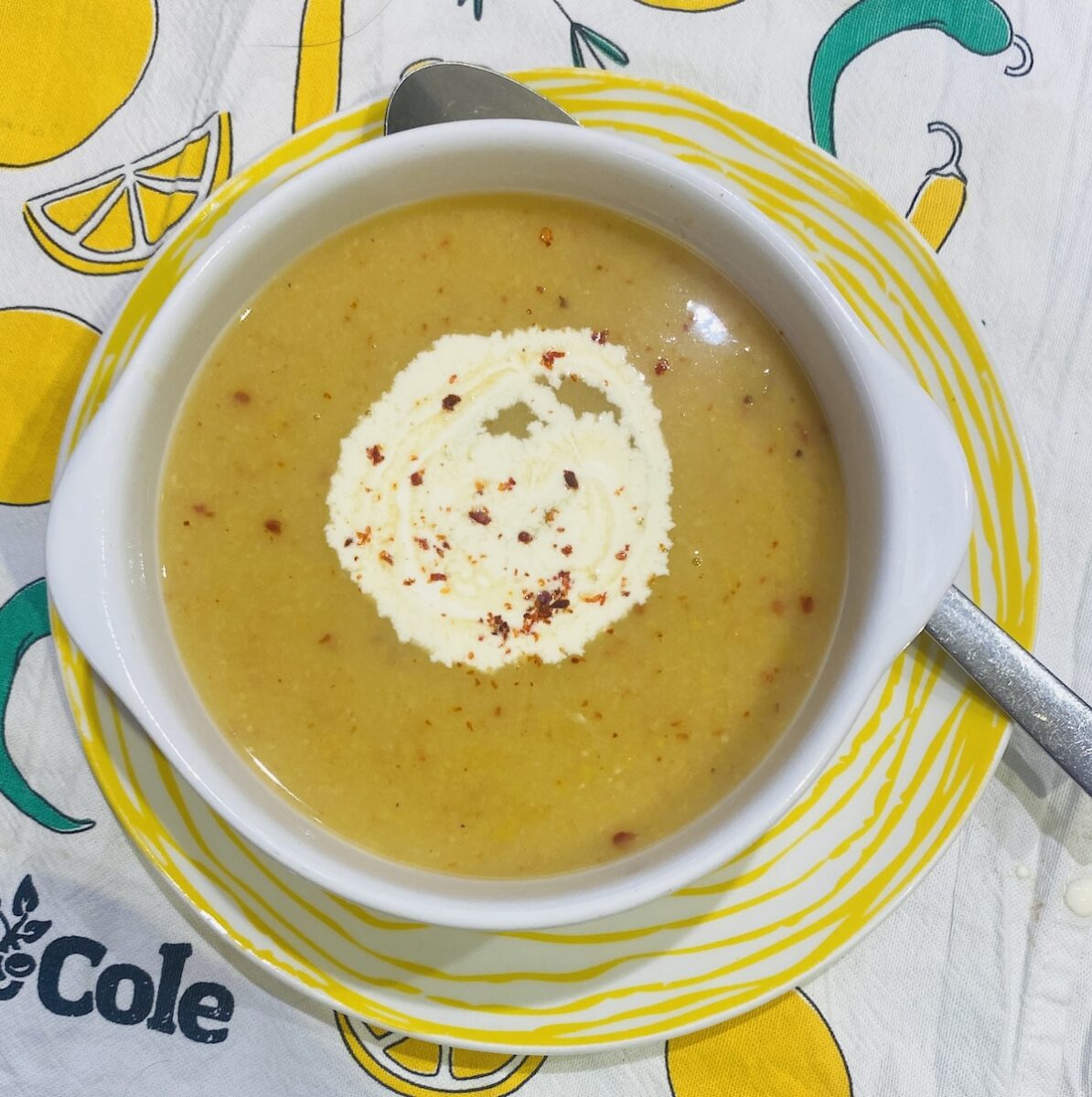 vegan split pea soup, in a white bowl, on a yellow striped plate.